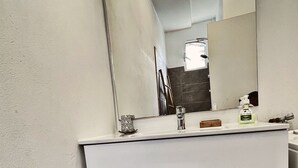 Casa de banho moderna com toucador branco, espelho e torneira.