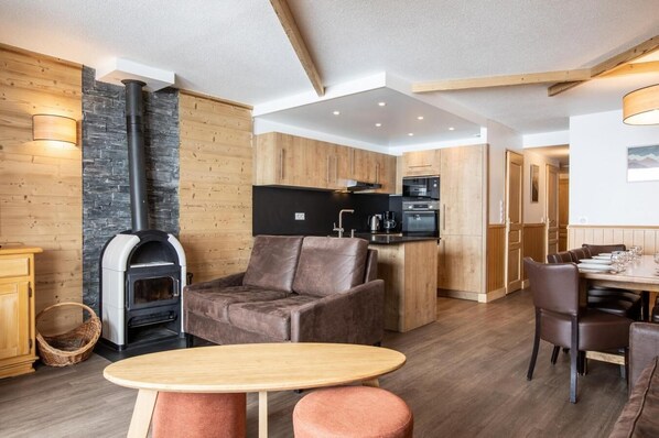 A modern living room with a fireplace, wooden furniture, and a dining area.