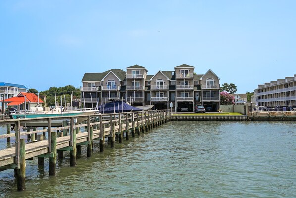A waterfront hotel with multiple balconies, a dock with boats, and a clear view of the water.