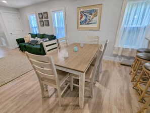 Ein Essbereich mit Holztisch und Stühlen, einem grünen Sofa und einem Bild an der Wand.