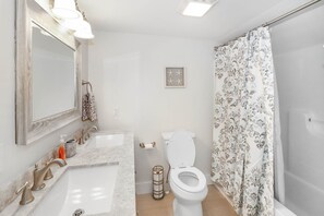 A bathroom with a double sink, toilet, and shower. - Stella del Mare | Remodeled South Main Cottage Walk Downtown w/ Patio Dining, King Suite & Charm (Chincoteague Island)