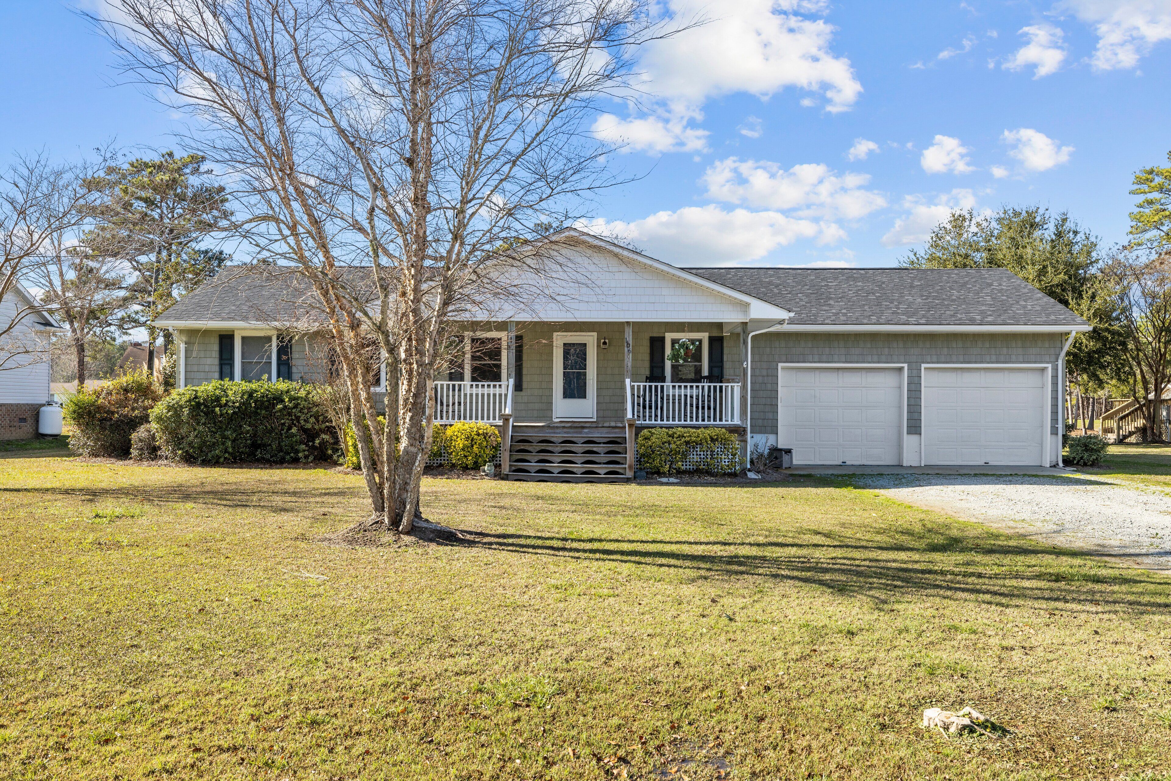 A single-story house with a front porch, a garage, and a well-maintained lawn.