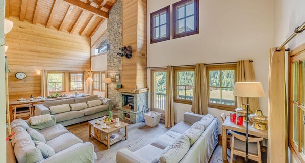 Cozy living area with a stone fireplace, comfortable seating, and large windows offering views of the surrounding landscape.