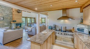 Enjoy cooking and relaxing in this well-appointed kitchen and living area, featuring a spacious island, comfortable sofa, and cozy fireplace.