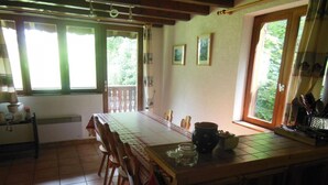 A kitchen with a long wooden table, chairs, a stove, and a window with curtains. - 2nd floor, view village, balcony, tv, ski locker, 75m², Champagny-en-Vanoise (Champagny-en-Vanoise)