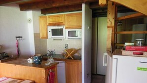 A kitchen with wooden cabinets, a microwave, a refrigerator, and a dining area with a table and chairs. - 2nd floor, view village, balcony, tv, ski locker, 75m², Champagny-en-Vanoise (Champagny-en-Vanoise)
