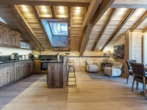 A spacious kitchen with wooden cabinetry and a central island, a cozy seating area with a fireplace, and a skylight above the kitchen.