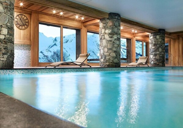 Enjoy a serene alpine view from the indoor pool, surrounded by lounge chairs for relaxation.