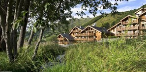 Escape to a tranquil retreat amidst lush greenery and rolling hills, surrounded by traditional Alpine-style cabins with balconies.