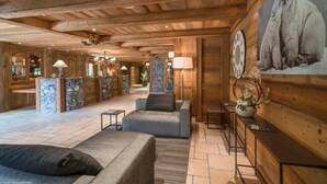 A wooden interior with a stone reception desk, a sofa, and a wall-mounted clock. - 200m from resort center, 1st floor, view ski slopes, fitness, swimming pool, sauna, hammam, terrace (Saint-Martin-de-Belleville)