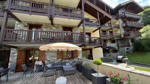 A multi-story building with balconies, outdoor seating, and a grill area.