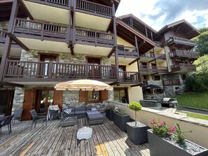 Un immeuble à plusieurs étages doté de balcons, d’un espace extérieur aménagé pour s’asseoir et d’un coin barbecue.