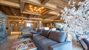 A cozy log cabin interior with a large gray sofa, a coffee table with magazines, and a fireplace. - 200m from resort center, 1st floor, view ski slopes, fitness, swimming pool, sauna, hammam, terrace (Saint-Martin-de-Belleville)