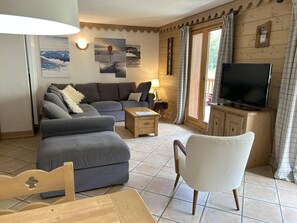 A cozy living room with a sofa, armchair, TV, and a small table.