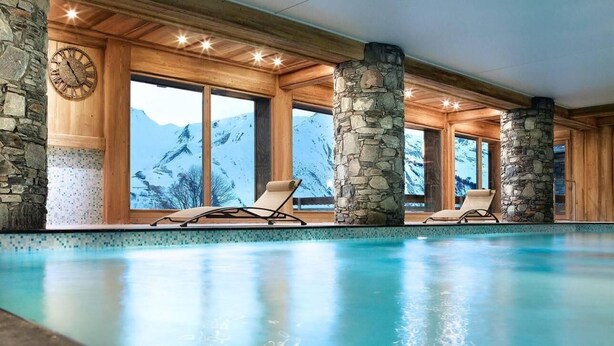 An indoor swimming pool with stone pillars, wooden beams, and a view of mountains. - 200m from resort center, 4th floor, view valley, fitness, swimming pool, sauna, hammam, balcony (Saint-Martin-de-Belleville)
