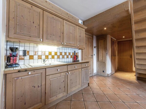 Una cocina con armarios de madera, salpicadero de azulejos y una cafetera.