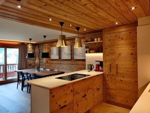 Una cocina moderna con armarios de madera, una isla central, iluminación colgante y un salpicadero de pared de piedra.
