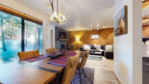 A modern dining area with a wooden table, leather chairs, and a chandelier. - Pet-Friendly, Bright Modern Gem, Gas Grill, Near Trails, Quiet Location (Mammoth Lakes)