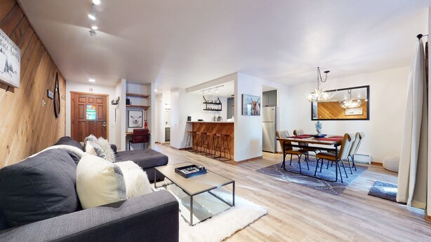 A modern living room with a sofa, coffee table, and a dining area with a table and chairs. - Pet-Friendly, Bright Modern Gem, Gas Grill, Near Trails, Quiet Location (Mammoth Lakes)