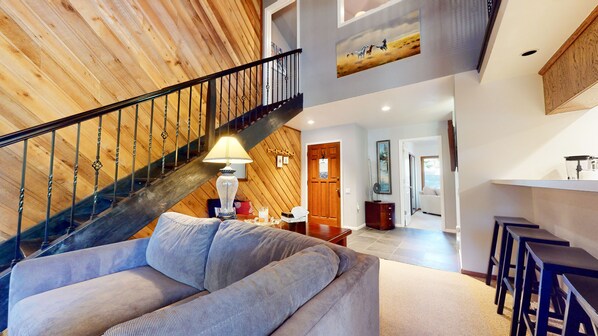 Relax in this stylish living area with a high ceiling, comfortable sofa, and modern staircase.