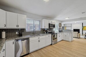Une cuisine moderne avec des meubles blancs, un lave-vaisselle, un four à micro-ondes et une cuisinière.