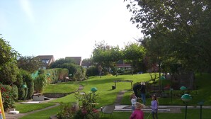 Un jardin bien entretenu, doté d’un chemin pavé, d’un petit espace de jeux et d’une grande variété de plantes et de fleurs.