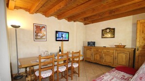 A cozy room with a wooden dining table, chairs, a television, a clock, and a sofa. - Crève Tête 3 rooms 60 m2 200 m from the free bus stop and 300 m from the ski lift (LES AVANCHERS VALMOREL)