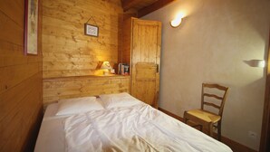 A wooden room with a bed, a chair, and a door. - Crève Tête 3 rooms 60 m2 200 m from the free bus stop and 300 m from the ski lift (LES AVANCHERS VALMOREL)