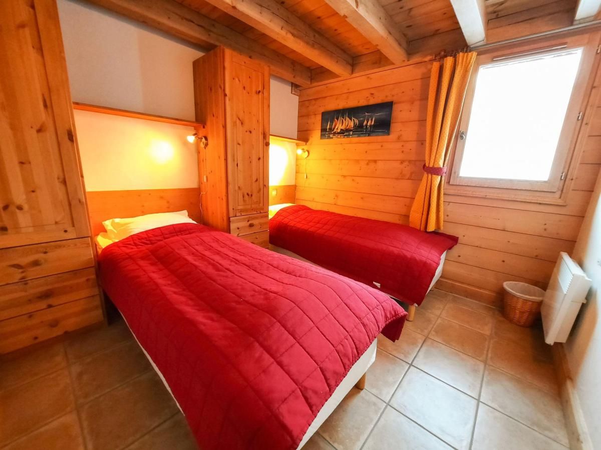 Een houten kamer met twee bedden, een raam met gordijnen en een aan de muur hangend schilderij.