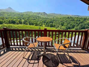 A wooden deck with two round tables and four chairs, overlooking a lush green landscape with hills in the background. - 300m from ski lifts, 2nd floor, balcony, tv, ski locker, 71m², Les Menuires (Saint-Martin-de-Belleville)