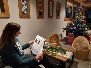 A person reading a magazine in a room with a Christmas tree and holiday decorations. - 50m from ski slopes, 3rd floor, view valley, fitness, swimming pool, sauna, hammam, balcony (Bourg-Saint-Maurice)