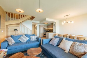 A modern living room with two sofas, a coffee table, and a staircase leading to an upper level. - 50m from ski slopes, 3rd floor, view valley, fitness, swimming pool, sauna, hammam, balcony (Bourg-Saint-Maurice)