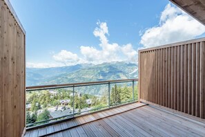 A balcony with a wooden floor and glass railing, offering a view of a mountainous landscape. - 50m from ski slopes, 3rd floor, view valley, fitness, swimming pool, sauna, hammam, balcony (Bourg-Saint-Maurice)