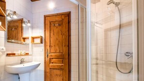 Une salle de bain avec une porte en bois, un lavabo blanc et une douche en verre.