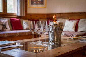 Une table en bois avec une bouteille de champagne et quatre verres dans un seau en métal.