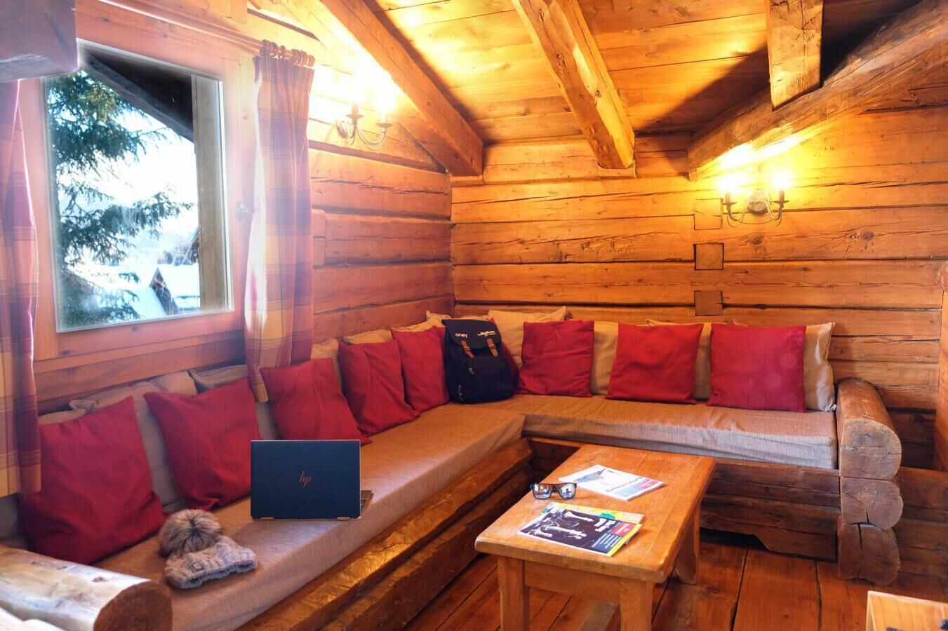 En stuga med träpanel på insidan, med en soffa, en bärbar dator och ett bord med tidskrifter.