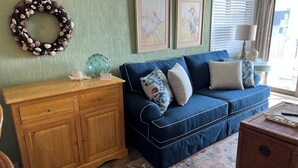 Ein Wohnzimmer mit blauem Sofa, Holzschrank und einem dekorativen Kranz an der Wand.