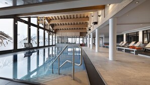 A spacious indoor swimming pool with clear glass walls, wooden beams, and sun loungers. - Wifi, ski-in/ski-out & foot of the slopes, view mountain, fitness, swimming pool, sauna, hammam (La Rosière Montvalezan)