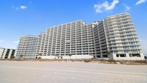 Un grande hotel pluripiano dal design moderno, con numerosi balconi e un tetto piano.
