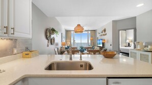 Una cucina moderna con una grande isola, lavello in acciaio inossidabile e zona pranzo con vista.