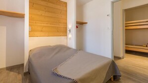 A small, neatly arranged bedroom with a wooden headboard, a single bed, and a built-in shelf. - 50m from ski slopes, balcony, tv, ski locker, 84m², Serre Chevalier (Briançon)