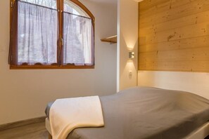 Cozy retreat with a single bed, wooden headboard, and wall-mounted light fixture.