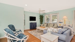 A living room with a sofa, armchairs, a coffee table, a TV, and a ceiling fan. - 4BR Cottage with Private Pool & Walk to Beach (Surfside Beach)
