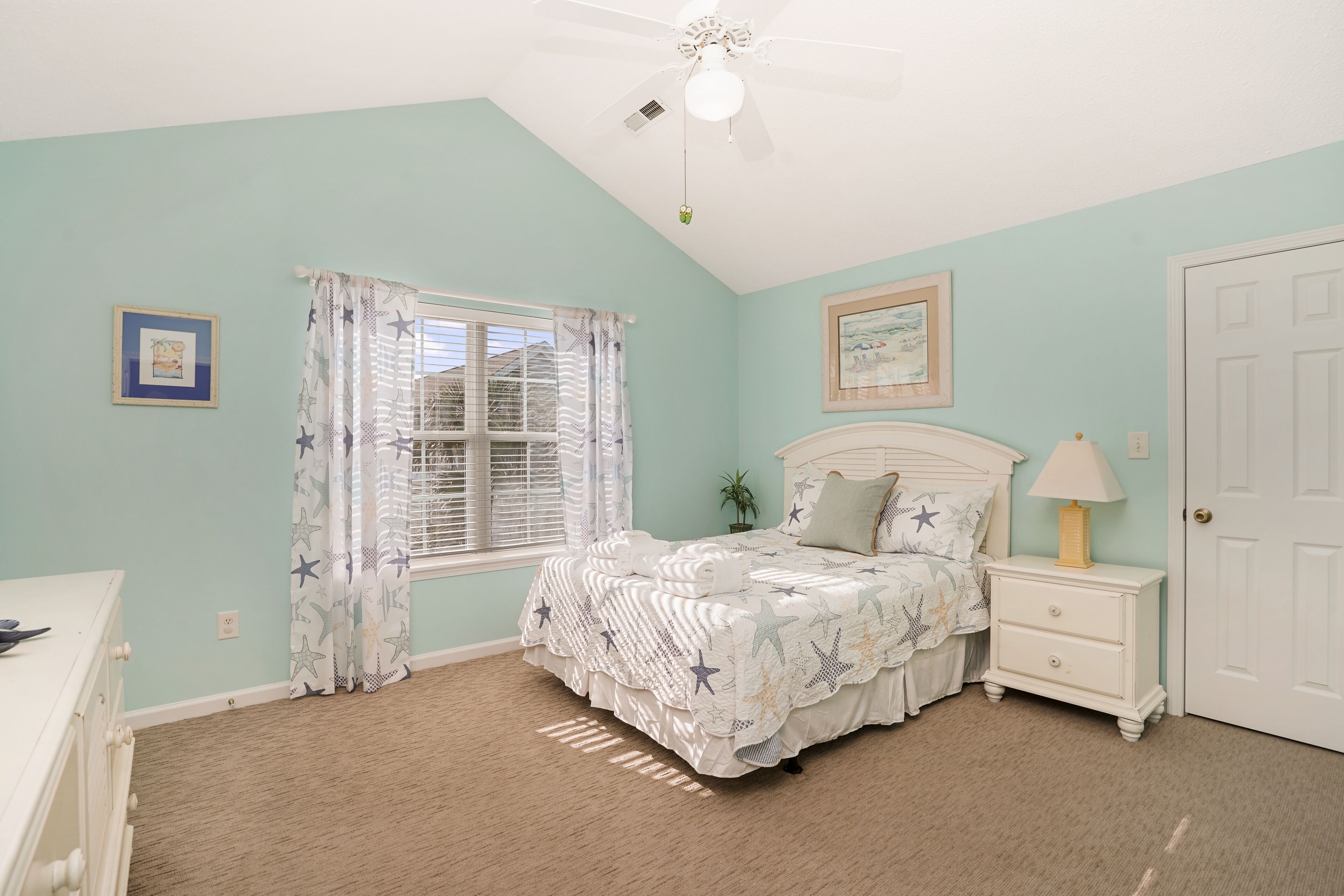 A bedroom with a bed, nightstand, and a ceiling fan.