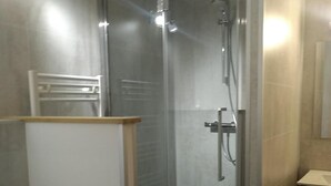 Uma casa de banho moderna com cabine de duche em vidro, sanita e toucador com espelho.