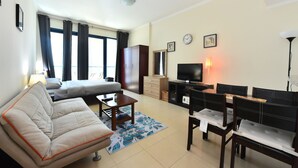 Una sala de estar con sofá, televisión, mesa y lámpara.