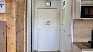 A narrow hallway with wooden cabinets on one side and a kitchenette on the other. - 300m from ski lifts, 3rd floor, balcony, tv, ski locker, 31m², Alpe d'Huez (L'Alpe d'Huez)