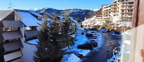 A residential area with snow-covered streets and buildings, including a multi-story hotel with balconies.
