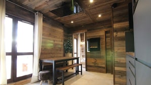 Una habitación acogedora con paredes de madera, una mesa de comedor con bancos, una chimenea y un televisor.