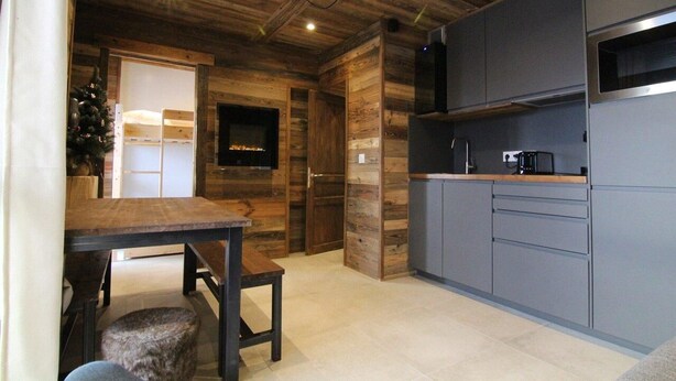 Una cocina moderna con detalles de madera, horno integrado y televisor de pantalla plana.
